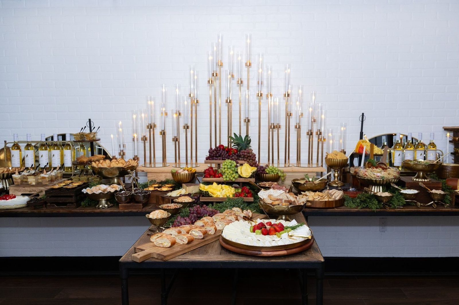 Grazing table set beneath rising gold candelabra